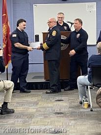 Firefighter Flora receives his certification from Chief Pollinger