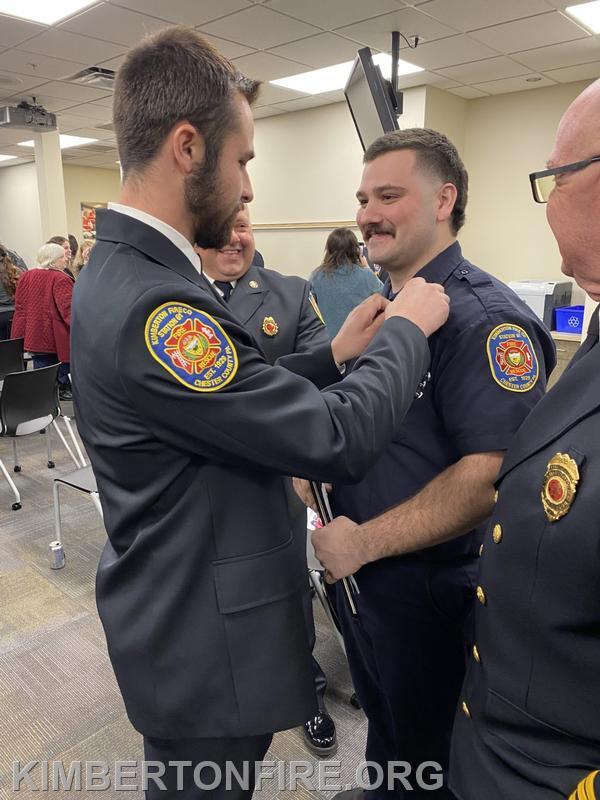 The pinning of the badge.  Lieutenant Bauer pins the badge on Louis's uniform.  